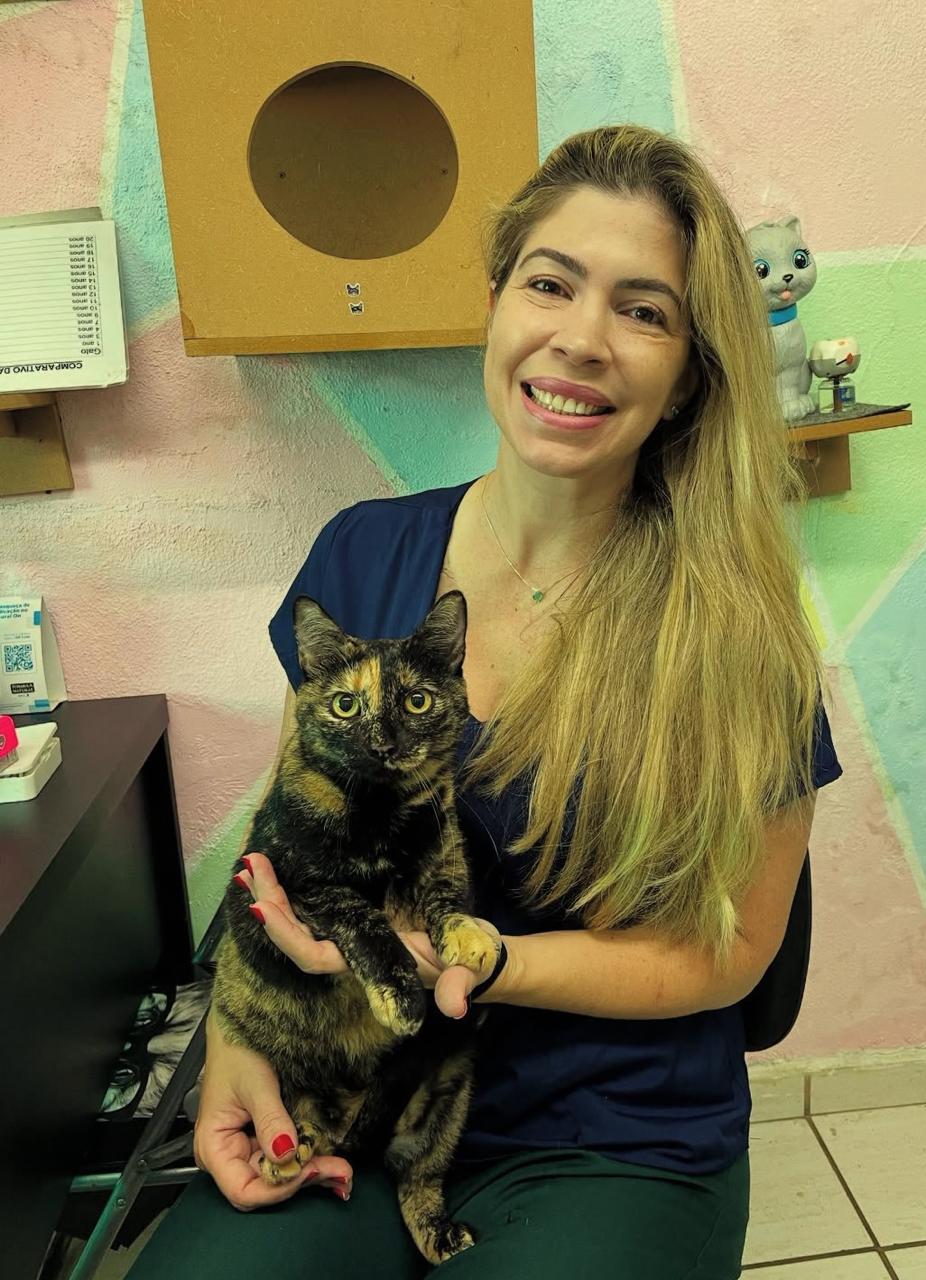 Dra. Bruna sorrindo e segurando uma gata tricolor (escama de tartaruga)